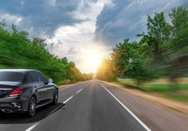 Araba, güneşli bir yaz gününde bir dağ yolunda hareket eder..