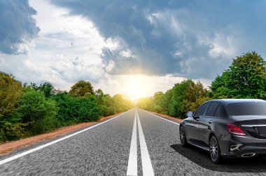 Araba, güneşli bir yaz gününde bir dağ yolunda hareket eder..