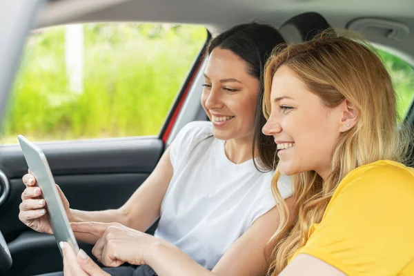 Unga kvinnor i bilen använder tabletten. — Stockfoto