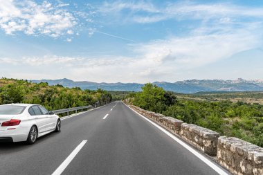 Araba yol boyunca gidiyor. Banliyö yolunda beyaz bir araba..