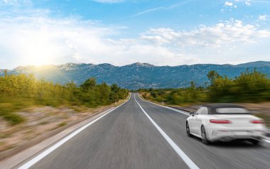 Araba yol boyunca gidiyor. Banliyö yolunda beyaz bir araba..