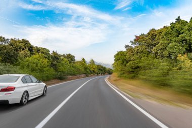 Araba yol boyunca gidiyor. Banliyö yolunda beyaz bir araba..