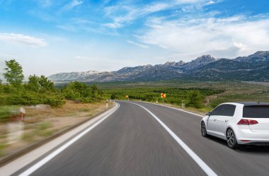 Araba yol boyunca gidiyor. Banliyö yolunda beyaz bir araba..