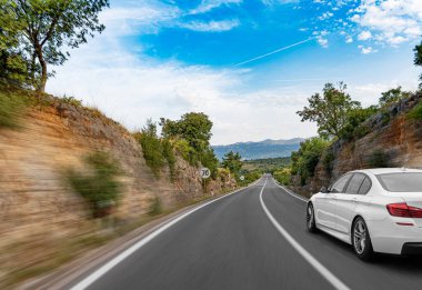 Araba yol boyunca gidiyor. Banliyö yolunda beyaz bir araba..