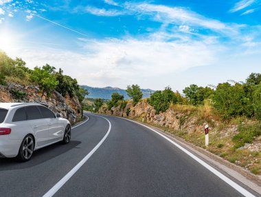 Araba yol boyunca gidiyor. Banliyö yolunda beyaz bir araba..