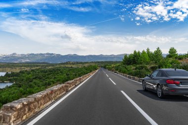 Manzaralı bir yolda siyah bir araba.