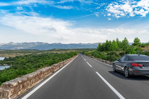 Manzaralı bir yolda siyah bir araba.