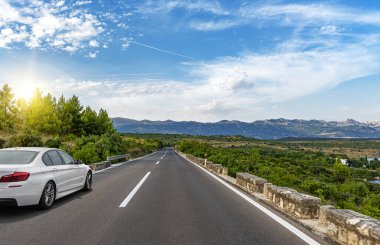 Araba yol boyunca gidiyor. Banliyö yolunda beyaz bir araba..