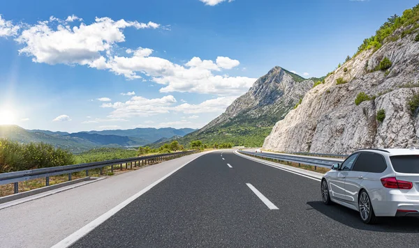 Araba yol boyunca gidiyor. Banliyö yolunda beyaz bir araba..