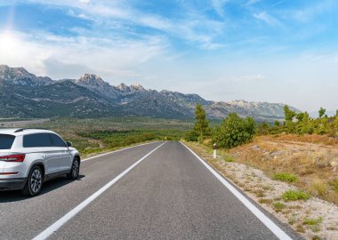 Araba yol boyunca gidiyor. Banliyö yolunda beyaz bir araba..