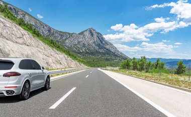 Araba yol boyunca gidiyor. Banliyö yolunda beyaz bir araba..