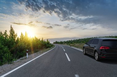 Manzaralı bir yolda siyah bir araba.