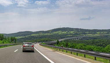KIA Ceed ve diğer arabalar Hırvatistan 'ın Plitvice kentinde bir köprüyle otoyol boyunca ilerliyorlar.