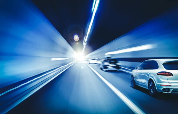 Carros correm através do túnel nos feixes de holofotes. — Fotografia de Stock