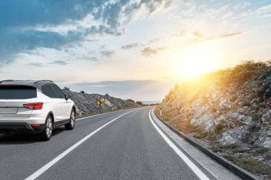 Araba yol boyunca gidiyor. Banliyö yolunda beyaz bir araba..