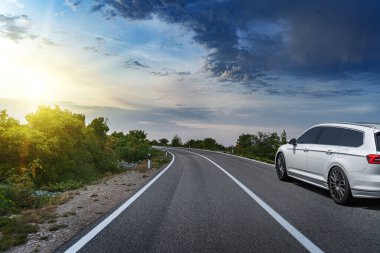 Araba yol boyunca gidiyor. Banliyö yolunda beyaz bir araba..