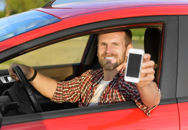 Uomo in auto guida mostrando smart phone . — Foto Stock