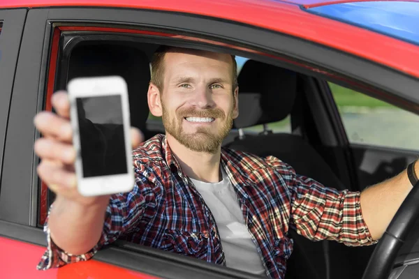 Homem no carro de condução mostrando telefone inteligente . — Fotografia de Stock