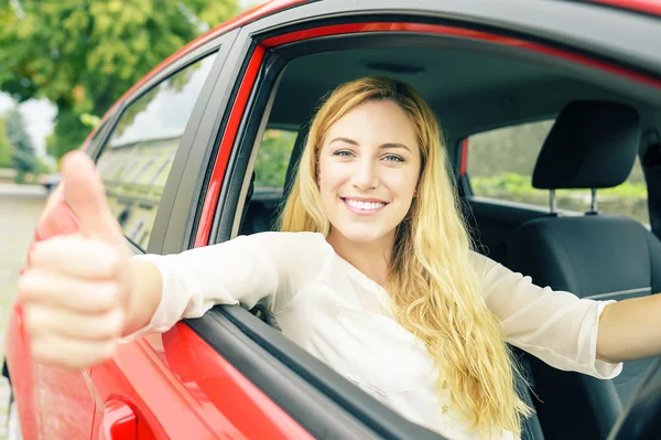 Gelukkig lachend meisje in een rode auto. — Stockfoto