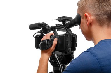 A professional cameraman operating a video camera on a tripod, focusing through the viewfinder against a white background.