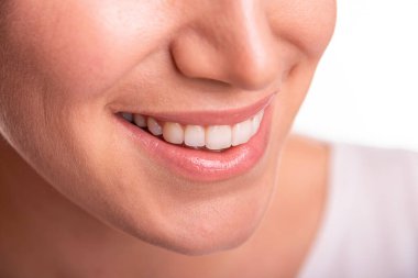 Gülümseyen bir kadının görüntüsü beyaz dişlerini ve doğal dudaklarını gösteriyor, mutluluğu, güveni ve diş sağlığını temsil ediyor..