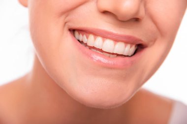 Gülümseyen bir kadının görüntüsü beyaz dişlerini ve doğal dudaklarını gösteriyor, mutluluğu, güveni ve diş sağlığını temsil ediyor..