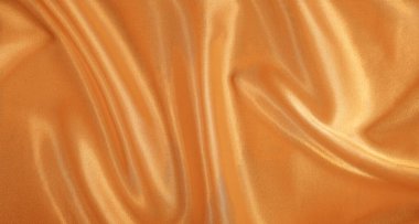 Yumuşak kıvrımları ve parlak bir yüzeyi olan pürüzsüz altın saten kumaş lüks ve zarif bir arkaplan oluşturuyor..