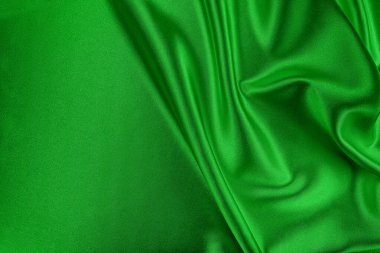 Bereketli yeşil saten ya da ipek kumaş örtülmüş ve katlanmış. Zarif dalgalar, doku ve ışıltılar yaratıyor. Lüks ve soyut bir arka plan için mükemmel..