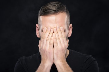 Adam elleriyle yüzünü kapsar.