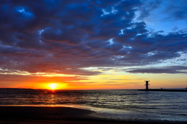 Pôr do sol sobre o mar com farol — Fotografia de Stock