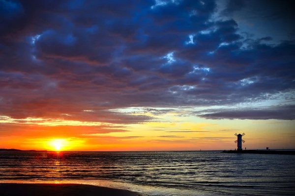 Pôr do sol sobre o mar com farol — Fotografia de Stock