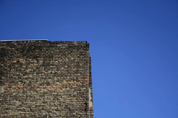 Antigua pared de ladrillo sobre un fondo de cielo azul —  Fotos de Stock