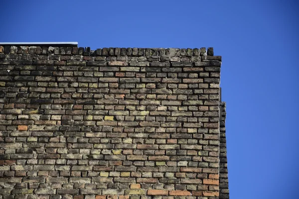 Antigua pared de ladrillo sobre un fondo de cielo azul — Foto de Stock