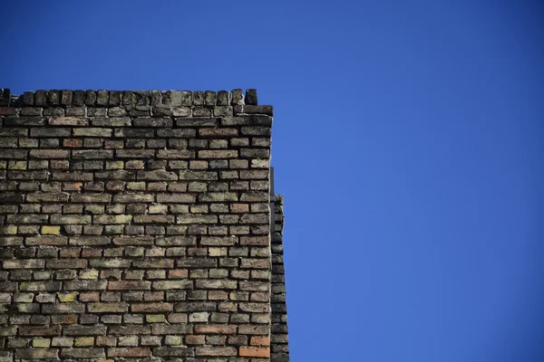 Parede de tijolo velha em um fundo de céu azul — Fotografia de Stock