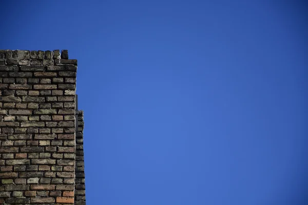 Antigua pared de ladrillo sobre un fondo de cielo azul — Foto de Stock