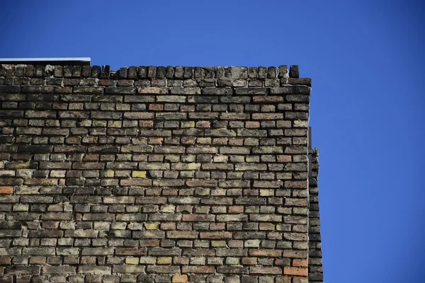 Parede de tijolo velha em um fundo de céu azul — Fotografia de Stock