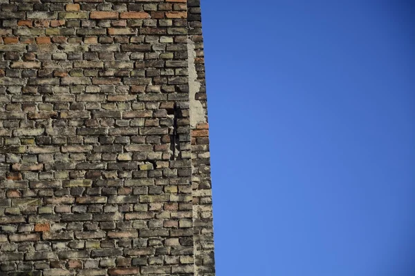 Parede de tijolo velha em um fundo de céu azul — Fotografia de Stock