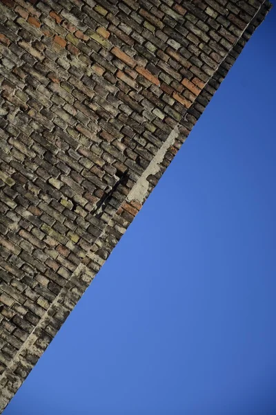 Antigua pared de ladrillo sobre un fondo de cielo azul — Foto de Stock