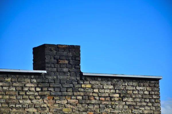 Parede de tijolo velha em um fundo de céu azul — Fotografia de Stock