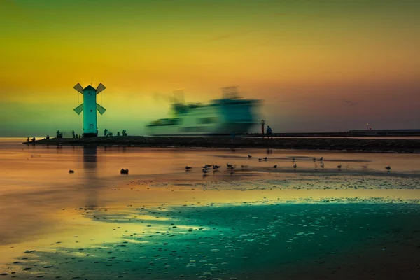 Faro - molino de viento contra el cielo - Swinoujscie —  Fotos de Stock