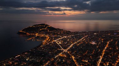 Türkiye 'nin Alanya kentinin insansız hava aracı tarafından ele geçirilmiş bir panoraması, aydınlık kenti, yarımadasını ve limanı sakin bir deniz ve alacakaranlık gökyüzüne karşı gösteriyor.