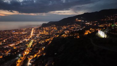 Türkiye 'nin Alanya kentinin insansız hava aracı tarafından ele geçirilmiş bir panoraması, aydınlık kenti, yarımadasını ve limanı sakin bir deniz ve alacakaranlık gökyüzüne karşı gösteriyor.