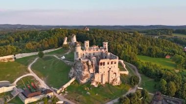 Polonya 'nın Ogrodzieniec kentindeki ortaçağ taş kalesinin insansız hava aracı saatleri dramatik kireçtaşı kayaları üzerinde yer alıyor ve kırsal alanla çevrili.