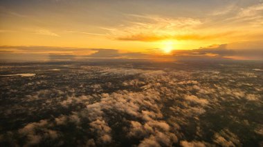 Yüksek irtifada bir hava fotoğrafı ağaçların arasından süzülen altın sabah sisi ile uçsuz bucaksız bir ormanın üzerinde gün doğumunu yakalıyor..