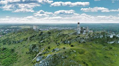 Polonya 'nın Çek Cumhuriyeti yakınlarındaki Olsztyn Kalesi' nin insansız hava aracı görüntüsü sıcak altın saat ışığıyla aydınlatılıyor. Jura Krakowsko-Çekoslovakya manzarasında küçük bir kasabanın üzerinde yükselen ortaçağ kireçtaşı kalesi.