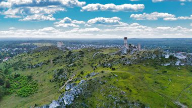 Polonya 'nın Çek Cumhuriyeti yakınlarındaki Olsztyn Kalesi' nin insansız hava aracı görüntüsü sıcak altın saat ışığıyla aydınlatılıyor. Jura Krakowsko-Çekoslovakya manzarasında küçük bir kasabanın üzerinde yükselen ortaçağ kireçtaşı kalesi.