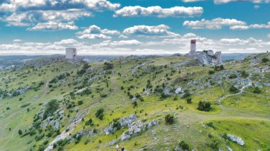 Polonya 'nın Çek Cumhuriyeti yakınlarındaki Olsztyn Kalesi' nin insansız hava aracı görüntüsü sıcak altın saat ışığıyla aydınlatılıyor. Jura Krakowsko-Çekoslovakya manzarasında küçük bir kasabanın üzerinde yükselen ortaçağ kireçtaşı kalesi.