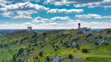 Polonya 'nın Çek Cumhuriyeti yakınlarındaki Olsztyn Kalesi' nin insansız hava aracı görüntüsü sıcak altın saat ışığıyla aydınlatılıyor. Jura Krakowsko-Çekoslovakya manzarasında küçük bir kasabanın üzerinde yükselen ortaçağ kireçtaşı kalesi.