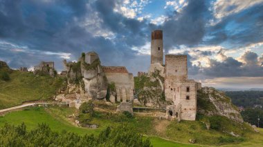 Polonya 'nın Çek Cumhuriyeti yakınlarındaki Olsztyn Kalesi' nin insansız hava aracı görüntüsü sıcak altın saat ışığıyla aydınlatılıyor. Jura Krakowsko-Çekoslovakya manzarasında küçük bir kasabanın üzerinde yükselen ortaçağ kireçtaşı kalesi.