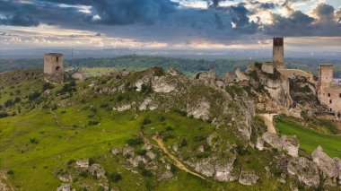 Polonya 'nın Çek Cumhuriyeti yakınlarındaki Olsztyn Kalesi' nin insansız hava aracı görüntüsü sıcak altın saat ışığıyla aydınlatılıyor. Jura Krakowsko-Çekoslovakya manzarasında küçük bir kasabanın üzerinde yükselen ortaçağ kireçtaşı kalesi.